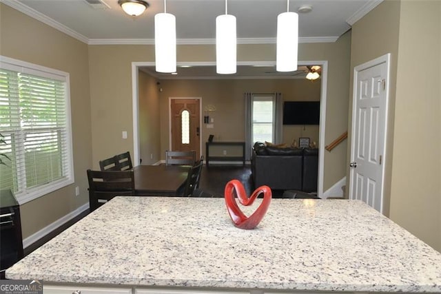 kitchen featuring dark wood-type flooring, a kitchen island, baseboards, ornamental molding, and light stone countertops