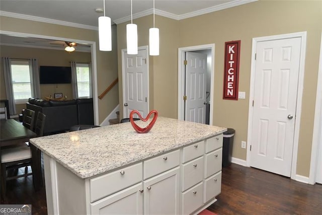 kitchen featuring dark wood-style floors, a kitchen island, white cabinets, and crown molding