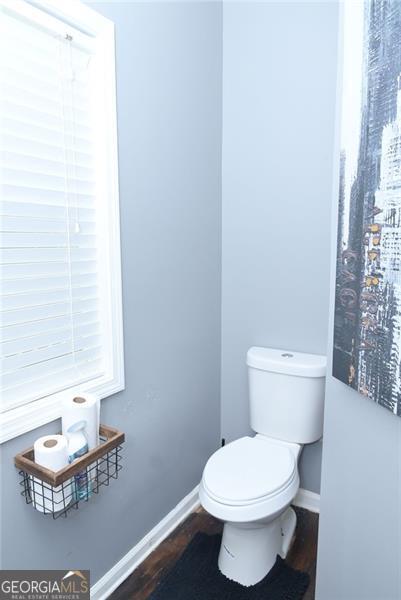 bathroom with toilet, baseboards, and wood finished floors