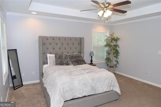 bedroom with ornamental molding, a tray ceiling, carpet flooring, and baseboards