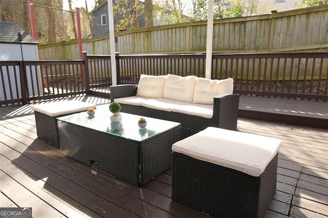 wooden deck featuring an outbuilding, outdoor lounge area, and a fenced backyard