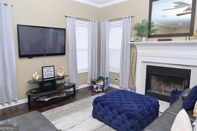 living room with a fireplace, a ceiling fan, crown molding, and wood finished floors