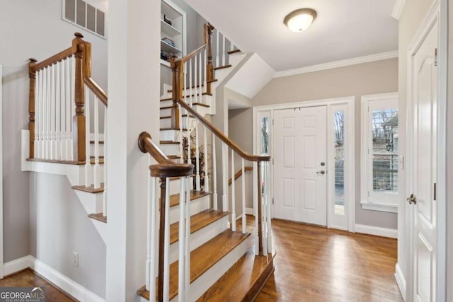 foyer with wood finished floors, visible vents, baseboards, ornamental molding, and stairway