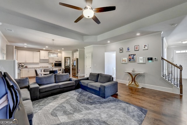 living area with ornamental molding, stairway, wood finished floors, and baseboards