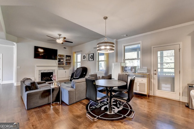 living area featuring a wealth of natural light, a high end fireplace, visible vents, and wood finished floors