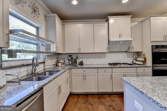 kitchen featuring backsplash, appliances with stainless steel finishes, white cabinets, a sink, and under cabinet range hood