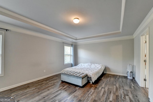 bedroom featuring ornamental molding, a tray ceiling, dark wood-type flooring, and baseboards