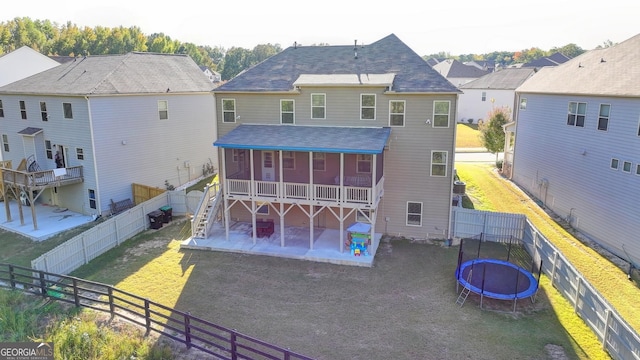 back of property featuring a fenced backyard, a sunroom, a yard, a trampoline, and a patio area