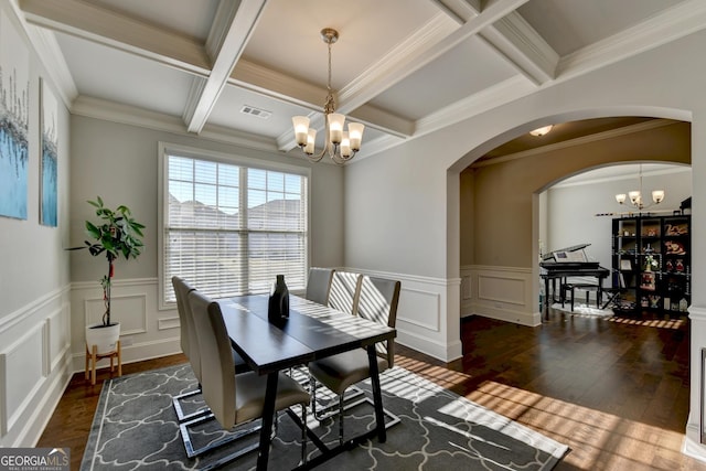 dining space featuring arched walkways, beam ceiling, wood-type flooring, an inviting chandelier, and coffered ceiling