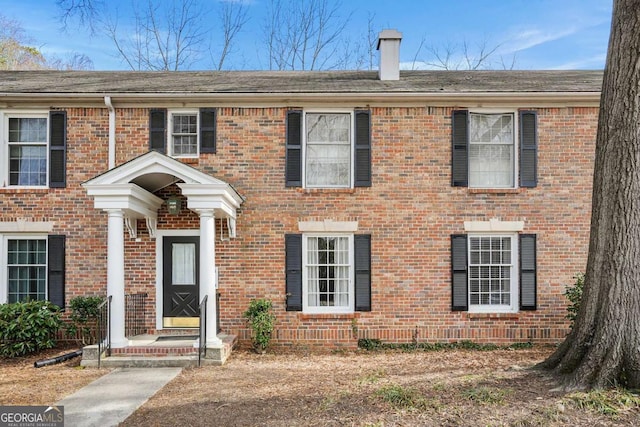 view of front of house featuring brick siding and a chimney