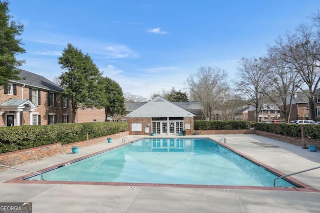 pool with a patio area, an outdoor structure, french doors, and an exterior structure