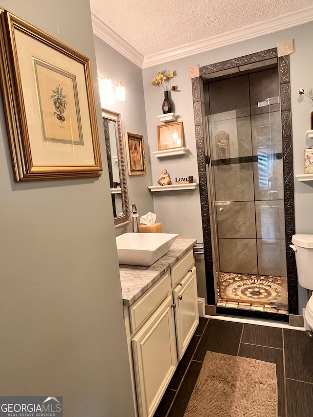 bathroom featuring toilet, ornamental molding, a shower stall, a textured ceiling, and vanity