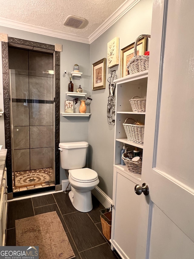 bathroom featuring wood finish floors, toilet, ornamental molding, a shower stall, and a textured ceiling