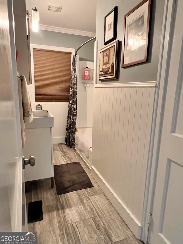 bathroom with visible vents, a shower with curtain, ornamental molding, wood finished floors, and vanity