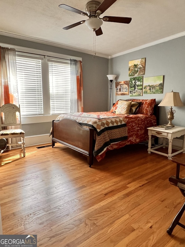 bedroom featuring ceiling fan, a textured ceiling, wood finished floors, and crown molding