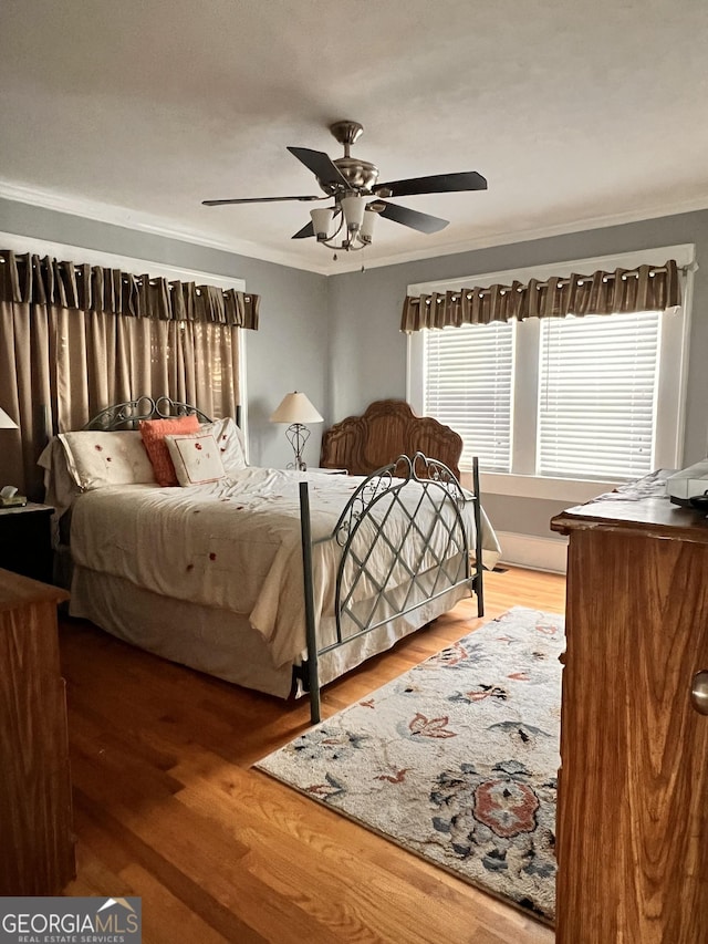 bedroom with ceiling fan, crown molding, and wood finished floors