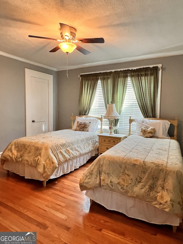 bedroom featuring ornamental molding, ceiling fan, a textured ceiling, and wood finished floors