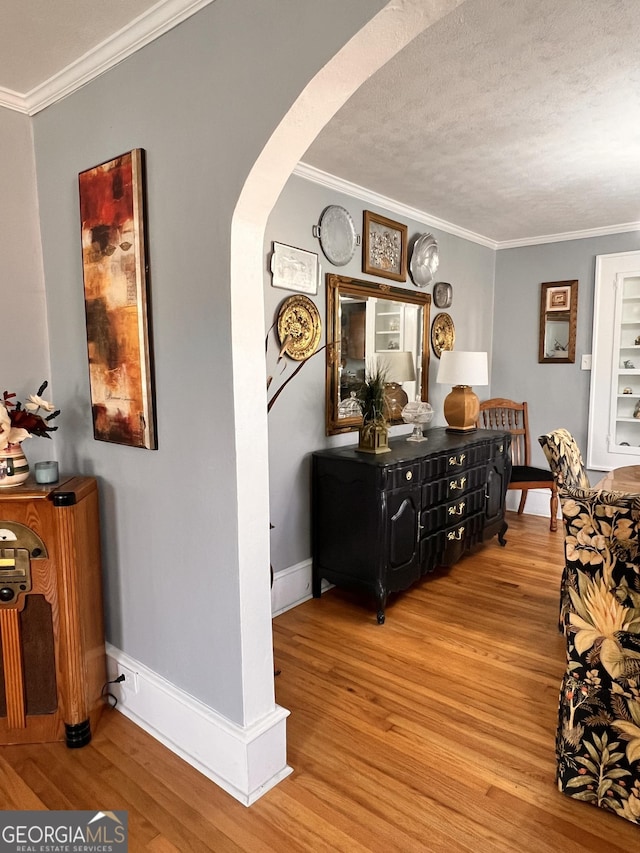 hallway featuring arched walkways, crown molding, and wood finished floors