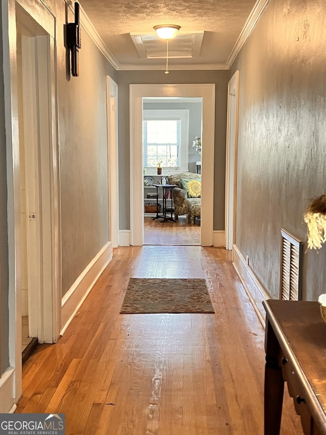 hallway featuring attic access, ornamental molding, and wood finished floors