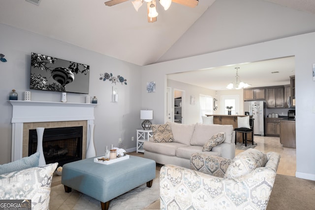 living area featuring lofted ceiling, baseboards, ceiling fan with notable chandelier, and a tile fireplace