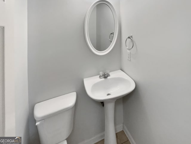 bathroom featuring baseboards, a sink, and toilet