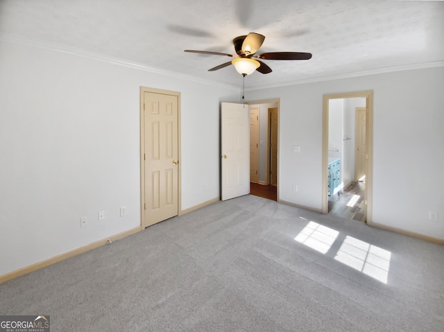 unfurnished bedroom with carpet, crown molding, ensuite bathroom, ceiling fan, and baseboards