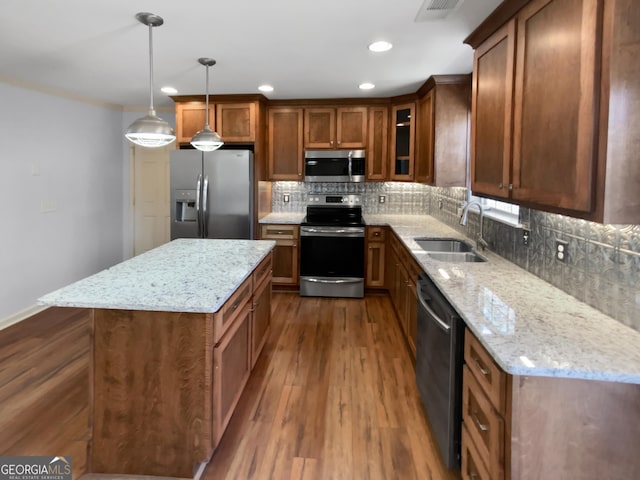 kitchen with dark wood finished floors, brown cabinetry, appliances with stainless steel finishes, a sink, and backsplash