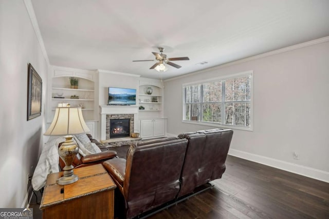 living area with baseboards, a ceiling fan, ornamental molding, dark wood-style flooring, and a fireplace