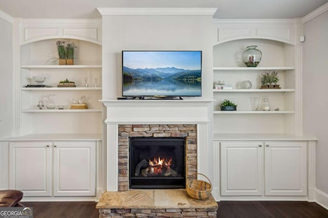 living area featuring crown molding, dark wood-style flooring, a fireplace, and built in features