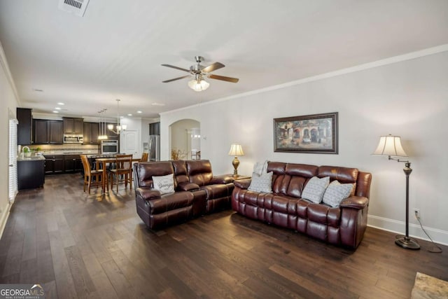 living room with arched walkways, dark wood-type flooring, visible vents, and crown molding