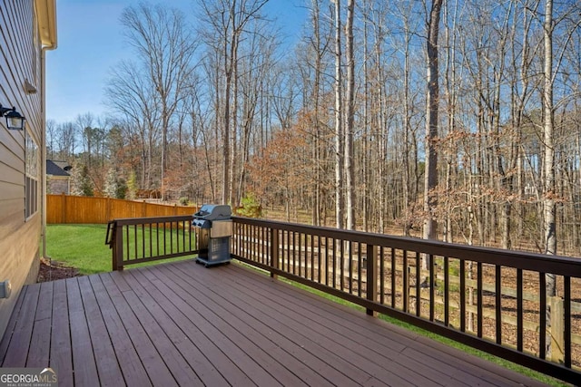 wooden terrace with a grill, a fenced backyard, and a yard