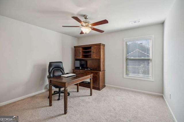 home office featuring visible vents, baseboards, a ceiling fan, and light colored carpet