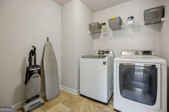 clothes washing area with laundry area, baseboards, and washer and dryer