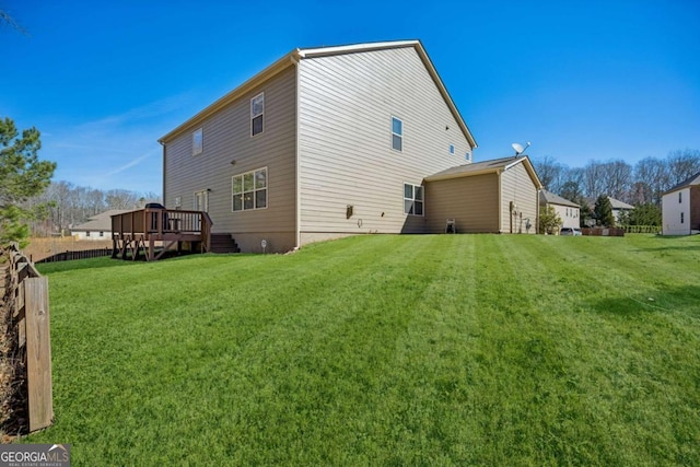 back of property featuring a lawn, a wooden deck, and fence