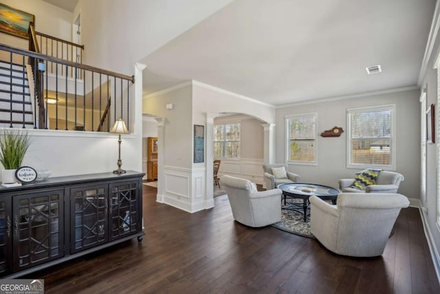 living room with decorative columns, visible vents, arched walkways, a wainscoted wall, and hardwood / wood-style floors