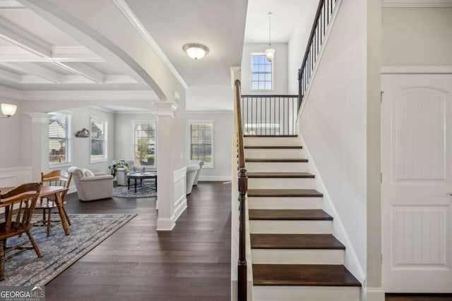 foyer entrance featuring decorative columns, ornamental molding, coffered ceiling, and dark wood-style flooring