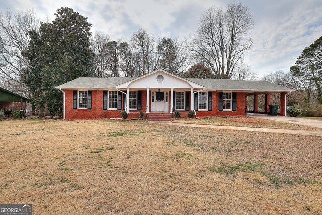 ranch-style home featuring brick siding, a porch, a carport, driveway, and a front lawn