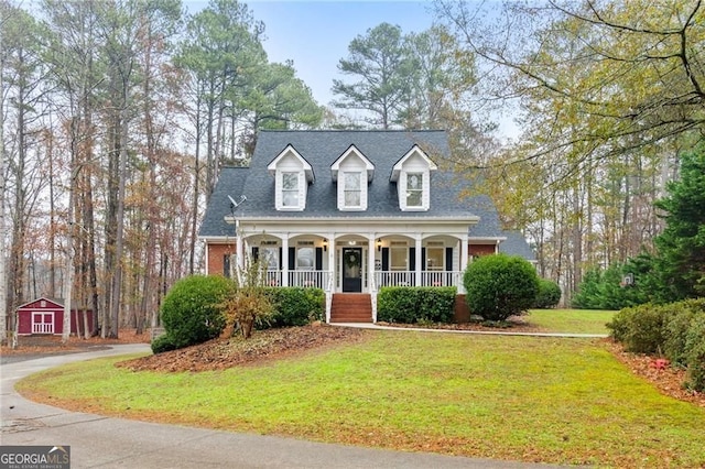 cape cod house featuring a front lawn, a porch, and a shingled roof