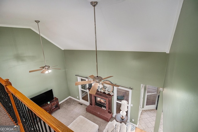 carpeted living room featuring a ceiling fan, a fireplace, baseboards, and ornamental molding