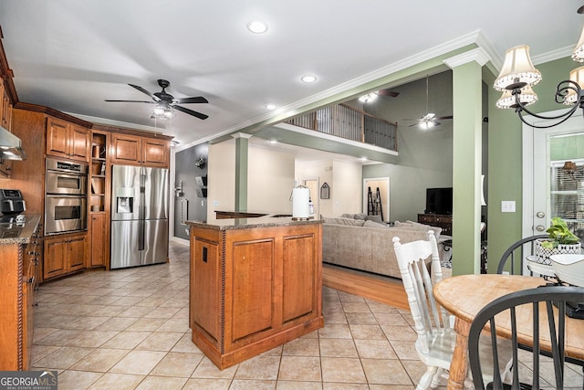 kitchen featuring brown cabinetry, ornamental molding, stainless steel appliances, and ceiling fan with notable chandelier