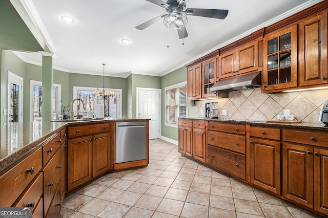 kitchen featuring tasteful backsplash, stainless steel dishwasher, brown cabinetry, a sink, and under cabinet range hood