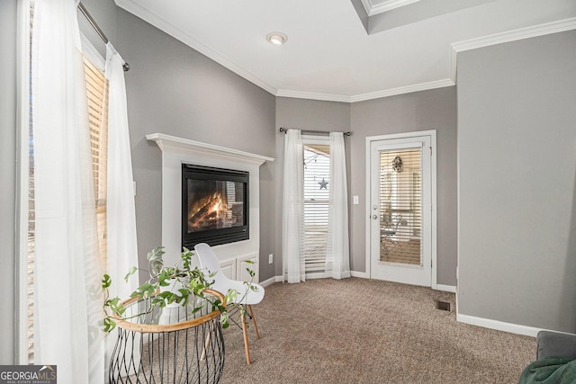 living area with baseboards, a glass covered fireplace, carpet flooring, and crown molding