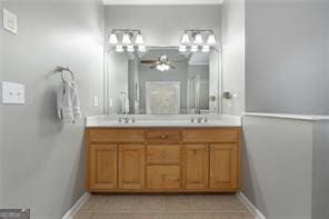 bathroom featuring tile patterned floors, a sink, baseboards, and double vanity