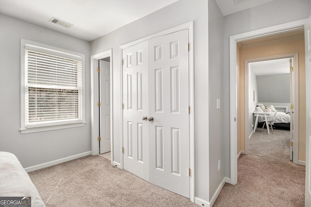 interior space with light colored carpet, a closet, visible vents, and baseboards