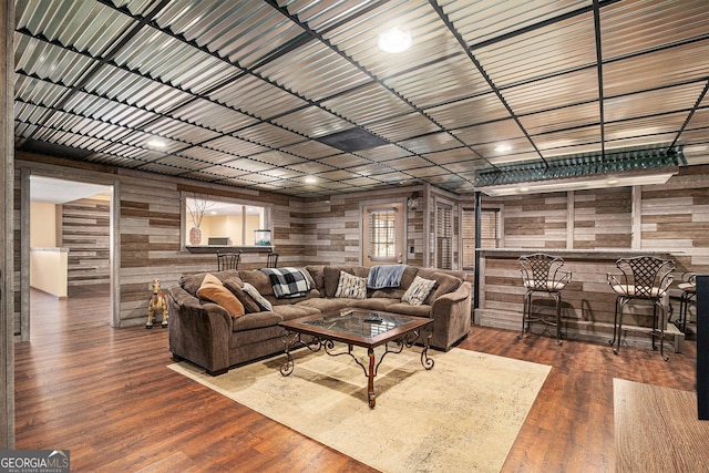 living area with metal wall, a dry bar, and wood finished floors