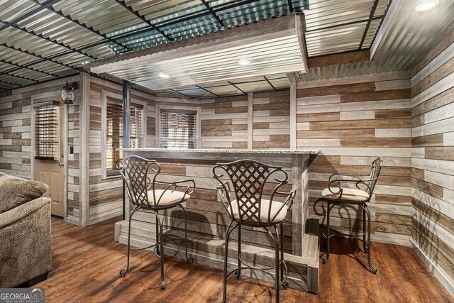 bar featuring a bar, wood walls, and wood finished floors