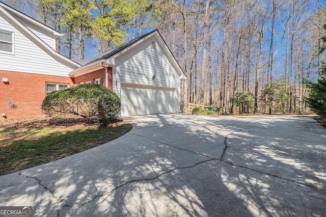 view of property exterior featuring brick siding, driveway, and an attached garage