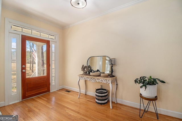 entrance foyer with a healthy amount of sunlight, light wood-style floors, baseboards, and ornamental molding