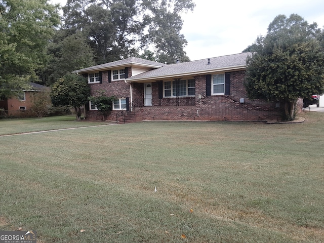 split level home featuring brick siding, roof with shingles, and a front yard