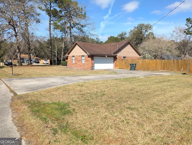 view of side of home featuring driveway, brick siding, a lawn, and fence